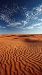 Vast Orange Sand Dunes Under Bright Blue Sky with Scattered White Clouds Arid Landscape Featuring Rippled Sand Texture Under Natural Sunlight High Angle View