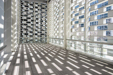 Modern architectural corridor with intersecting light and shadow on wooden flooring