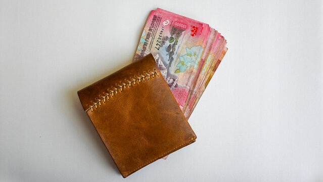 Indonesian Rupiah Banknotes in Brown Leather Wallet on White Background