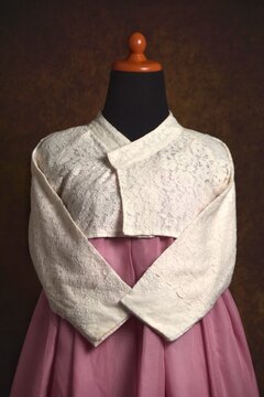 Semi-modern off-white lace hanbok on a mannequin in close-up. Hanbok consist of a blouse called jeogori and a skirt called chima.