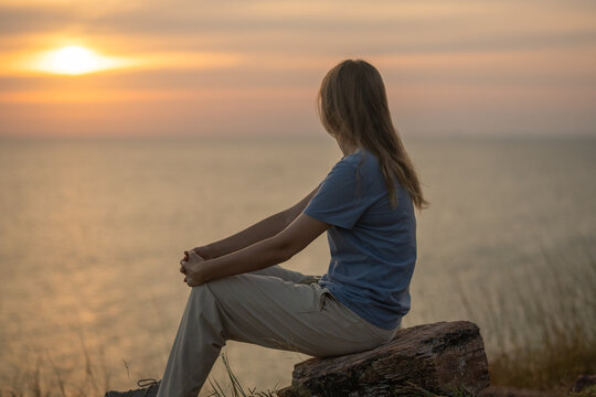 Hiker sitting on top of rocky cliff enjoying panoramic views under clear blue sky representing freedom adventure travel and peaceful moments in nature during  hiking journey