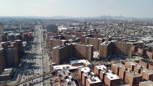 Sweeping aerial view showing the massive co op city housing cooperative in the bronx, new york city, with heavy traffic on the expressway and the distant manhattan skyline on a sunny winter day