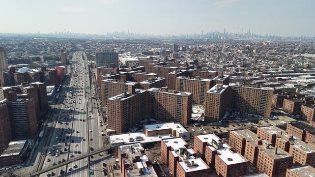 Expansive aerial perspective showing the busy bruckner expressway alongside the soundview public housing projects in the bronx. With the distant manhattan skyline visible on a cold. Sunny winter day