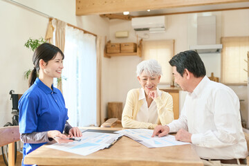 Obraz premium 訪問介護でプランの説明をするアジア人介護士