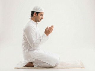 Fototapeta premium indian muslim man sitting and making dua with raised hands isolated on white background representing islamic prayer faith spirituality and religious devotion concept