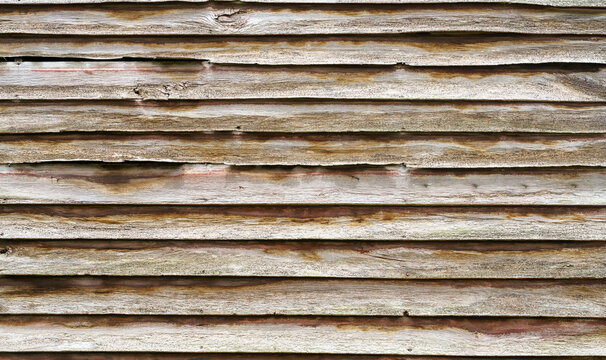 Weathered wooden siding texture with horizontal planks. Aged barn wood wall background showing grain, knots, and natural wear. Rustic timber surface for architectural or design backdrop.