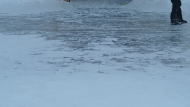Happy child in winter parka and ushanka hat sliding and falling on ice at outdoor rink. Cheerful boy laughing and enjoying active winter games on a frozen pond surface.