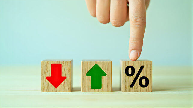 Hand pointing at wooden blocks with percentage symbol and up and down arrows on a table