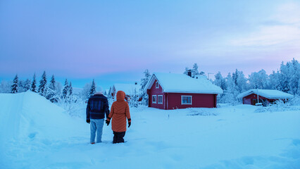 Naklejka premium Couple walks hand in hand through winter wonderland in Akaslompolo, Lapland, Finland