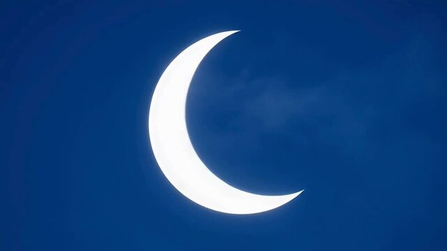 Crescent moon visible in a clear blue sky during a partial solar eclipse from a direct viewpoint