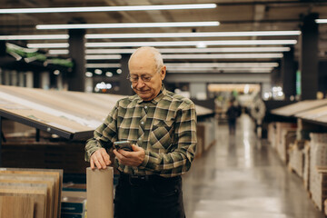 Fototapeta premium Senior man using smartphone in hardware store