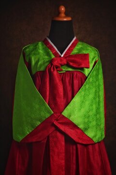 Bright neon green and red hanbok set on a mannequin. Hanbok consist of a blouse called jeogori and a skirt called chima