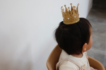 王冠をかぶる一歳児の後ろ姿。 © umaruchan4678