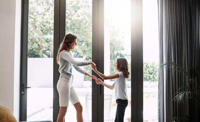 Obraz premium Happy, mother and child with dancing in home for bonding together, healthy relationship and support. Love, mom and kid with learning rhythm in apartment for weekend fun, connection and holding hands