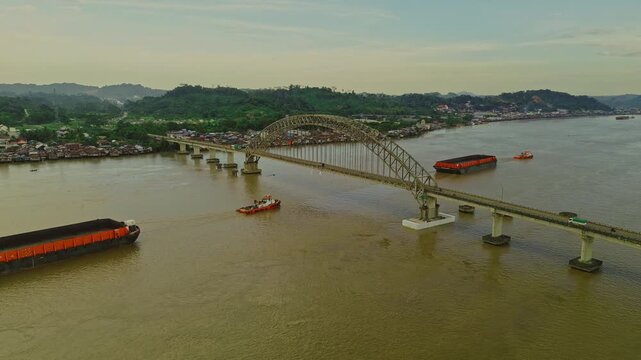 Aerial view of Mahulu Bridge (Mahakam Ulu) being passed by a coal tugboat on the Mahakam River, Samarinda