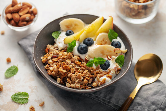Homemade crispy granola, yogurt, fruits and berries in bowl on white background. Healthy breakfast