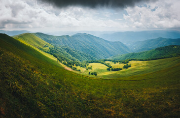 Vast verdant hills create a magnificent vista from the top over a gorgeous valley. Atmospheric place in the Carpathian mountains, Ukraine.