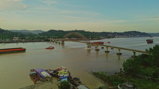Aerial view of Mahulu Bridge (Mahakam Ulu) being passed by a coal tugboat on the Mahakam River, Samarinda