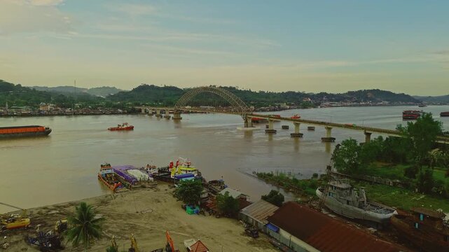 Aerial view of Mahulu Bridge (Mahakam Ulu) being passed by a coal tugboat on the Mahakam River, Samarinda