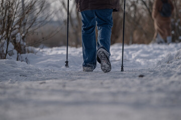 Senior man walking with trekking poles on snowy path