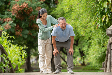 Young woman helping senior man fall accident hurt on floor in public park. Elderly male slipping and falling on bridge outdoors while walking suffering from knee pain with caregiver assistant.
