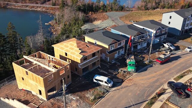 Aerial view: construction of high-end wooden frame houses in Beechville suburb of Halifax. Fresh timber structures show rapid housing development in Nova Scotia, Canada sunny day.
