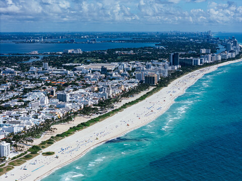 Aerial view of South Pointe Beach, Fisher Island, and Downtown Miami skyline under blue sky. c.