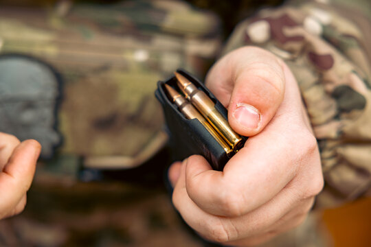 A female hand loading the AK-74 automatic rifle magazine, Ukrainian pixel camouflaged uniform as background
