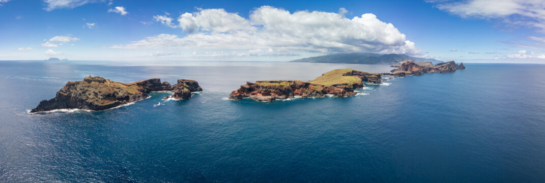 Aerial super wide panorama of Point of Saint Lawrence with Ilheus do Farol lighthouse, drone view fully reveals volcanic cape and Madeira Island rising behind the Atlantic