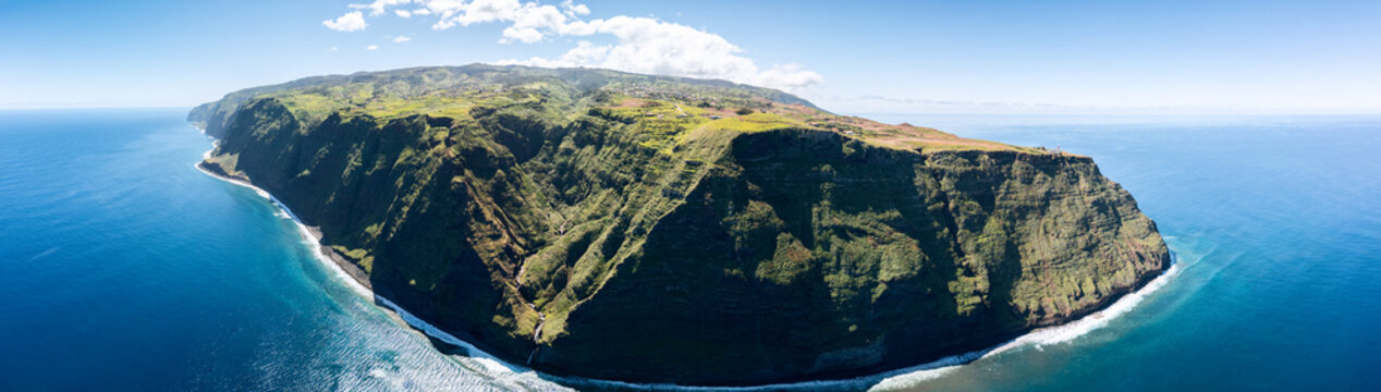 Aerial drone panorama of Ponta do Pargo cliffs Madeira Portugal, Atlantic coast vast green plateau above sheer ocean walls with winding gorges