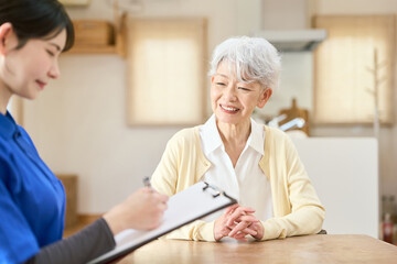 Obraz premium 介護士にヒアリングを受けるシニア女性