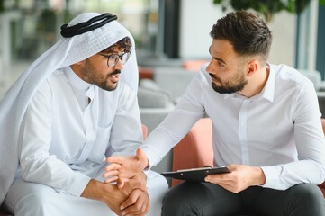 International operations manager meeting saudi business partner wearing traditional kandura
