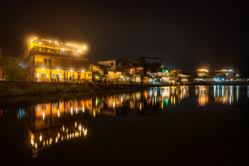Obraz premium Beautiful night riverside scene with warm light reflection at Pilok, Thong Pha Phum, Kanchanaburi, Thailand