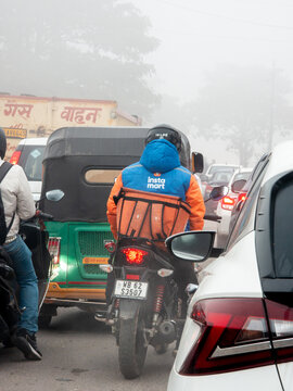 Swiggy Instamart rider driver stuck in a traffic jam on a foggy day showing the challenges faced by these gig workers for hyperlocal quick commerce