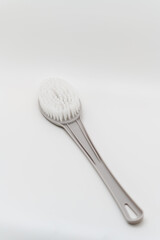 Brush with a long handle placed on a plain white surface
