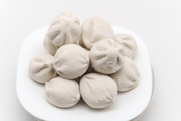 Soft dumplings sit on a white plate ready for preparation and cooking