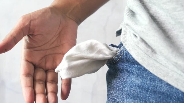 Young man showing empty pocket after pulling white lining out of blue jeans while standing against white background