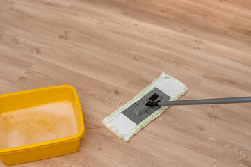 Washing the floor, close-up of a mop on a stick cleaning vinyl flooring in an apartment