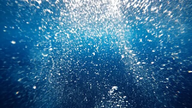 Sunlight piercing deep blue water with rising bubbles