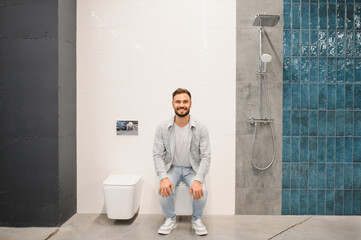 Man smiling sitting on toilet in showroom © Serhii