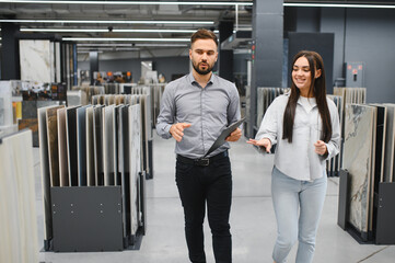 Seller assisting female buyer choosing tile in store