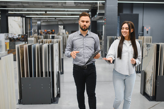 Seller assisting female buyer choosing tile in store