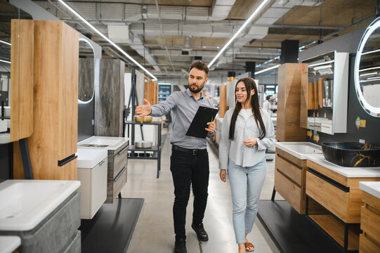 Salesman assisting customer choosing bathroom furniture in store