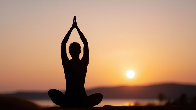 Woman practicing yoga at sunset with hands in prayer position  