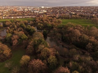 Obraz premium Aerial view of Birkenhead Park showing lakes, trees and walking paths under cloudy Merseyside skies.