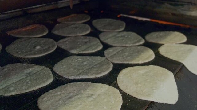 Close-up footage of traditional egyptian flatbread aish baladi baking in conveyor oven. Baking pita bread on traditional egyptian street baker shop