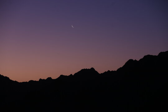 Crescent Moon Over Mountain Silhouette at Dusk with Gradient Twilight Sky
