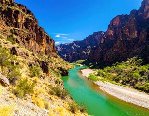 Vibrant turquoise river carving through a deep desert canyon under a bright blue sky.