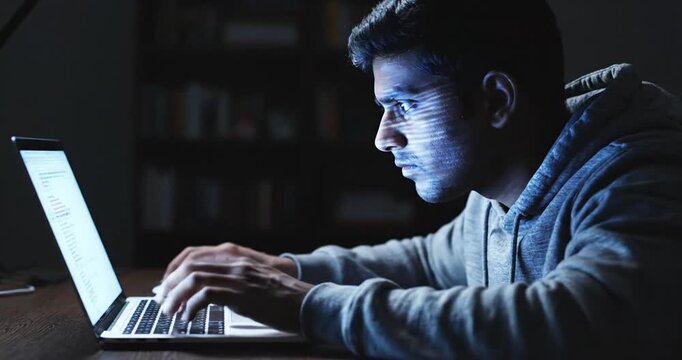 Focused individual working late at night on a laptop, illuminated by screen light in a cozy room