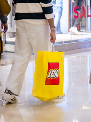 Fototapeta premium Customers carrying the iconic yellow and red themed LEGO bag from India's first store in ambience mall showing the popularity of this toy